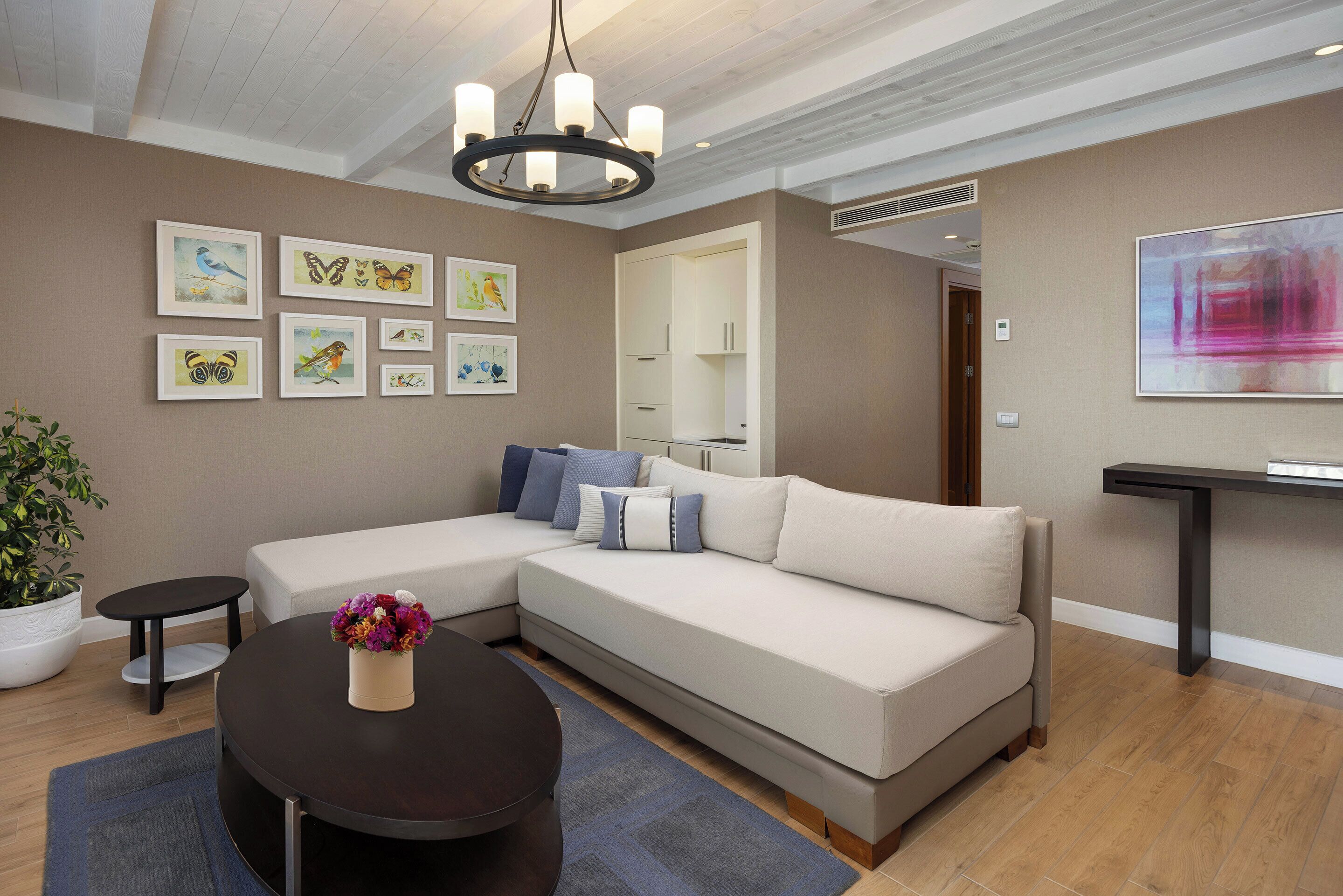 A modern living room with a sectional sofa, a round coffee table, and artwork on the walls.