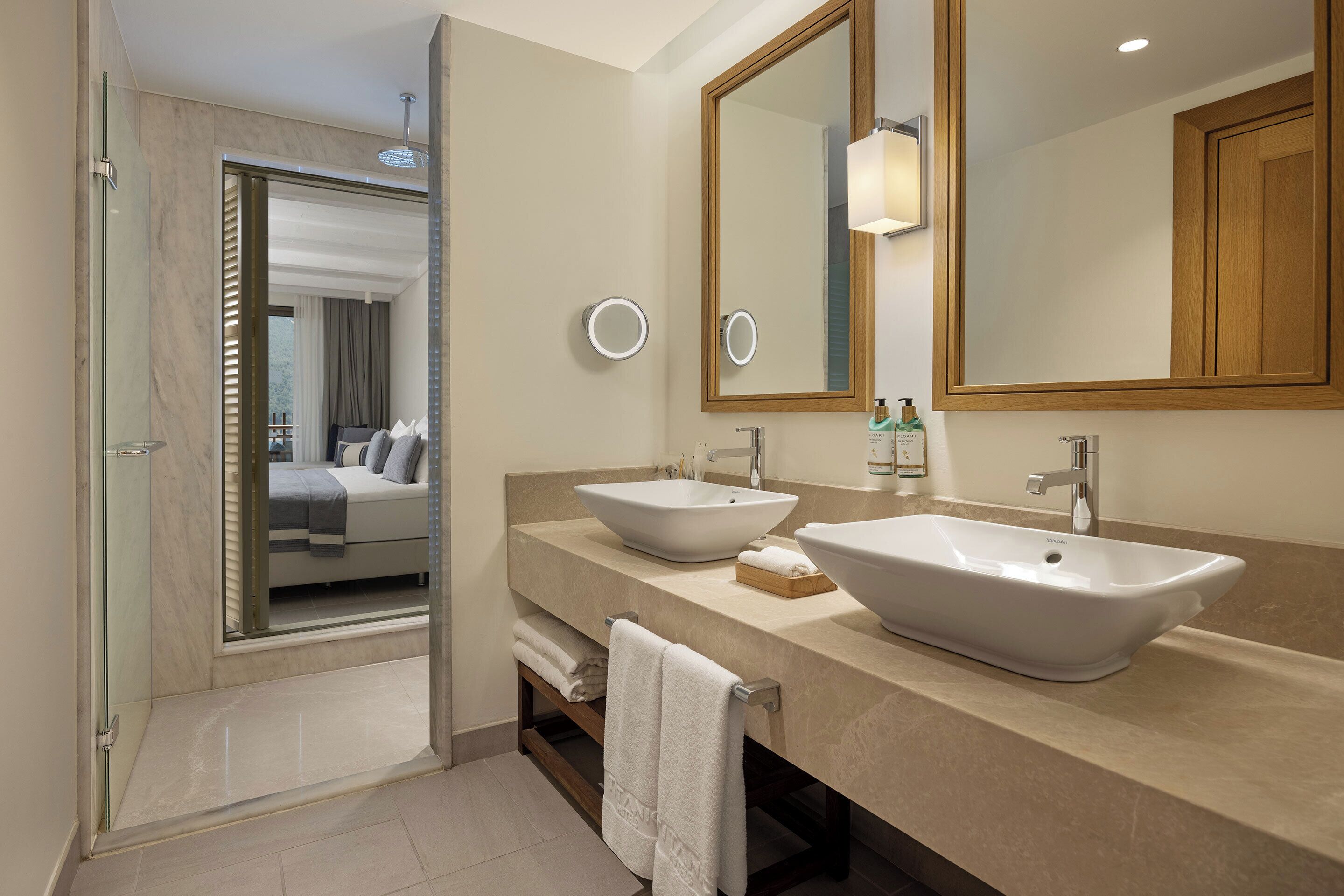 A modern bathroom with two sinks, a large mirror, and a glass shower enclosure.