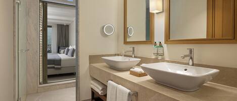 A modern bathroom with two sinks, a large mirror, and a glass shower enclosure.
