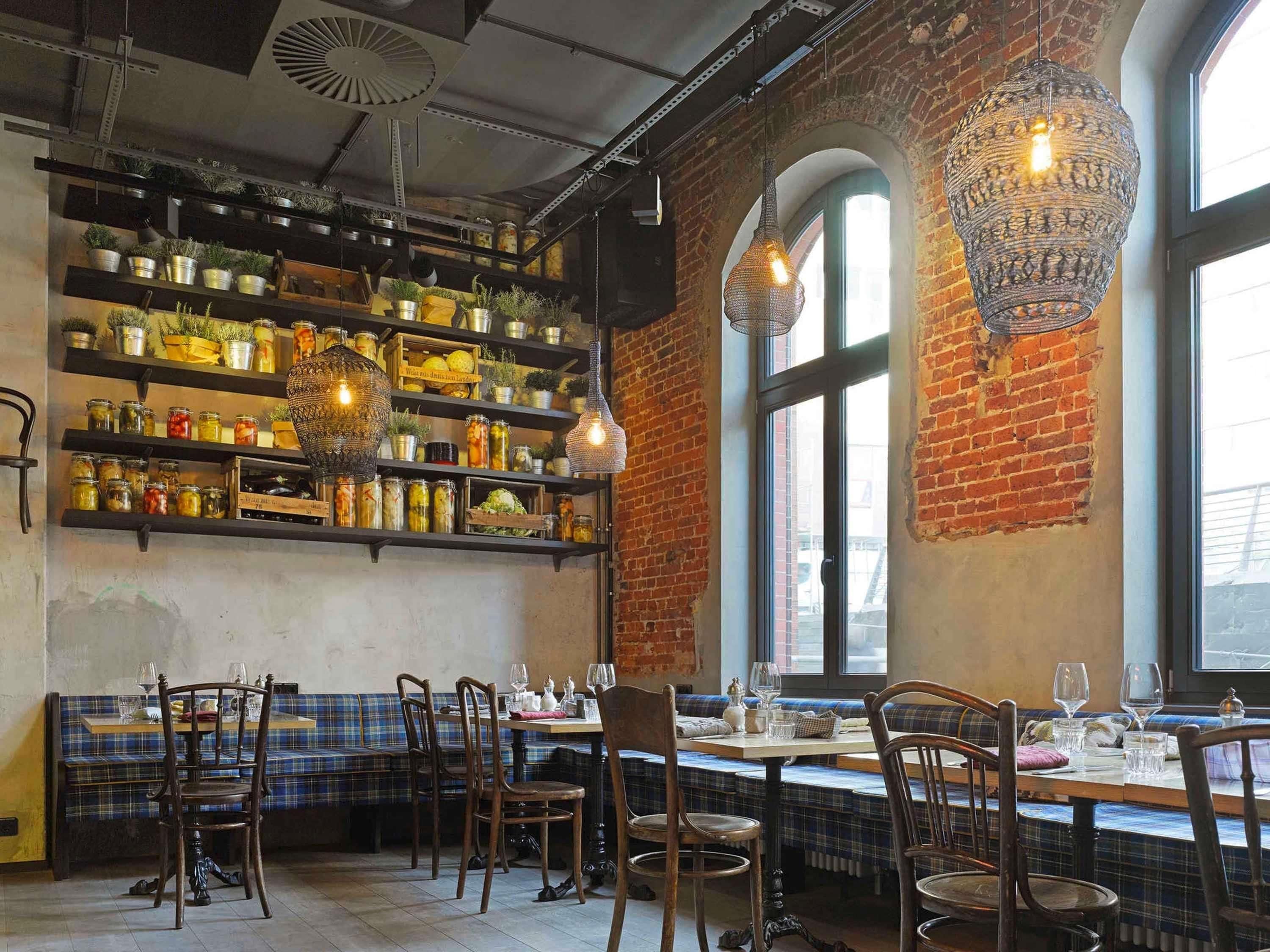 A restaurant interior with brick walls, wooden furniture, and shelves with jars.
