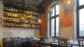 A restaurant interior with brick walls, wooden furniture, and shelves with jars.