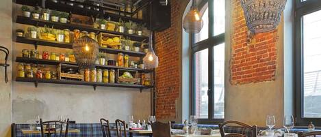 Interior de restaurante con paredes de ladrillo, muebles de madera y estanterías con frascos.