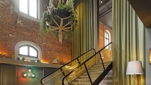 Un hall d’entrée spacieux avec un mur en briques, un escalier et des plantes suspendues.