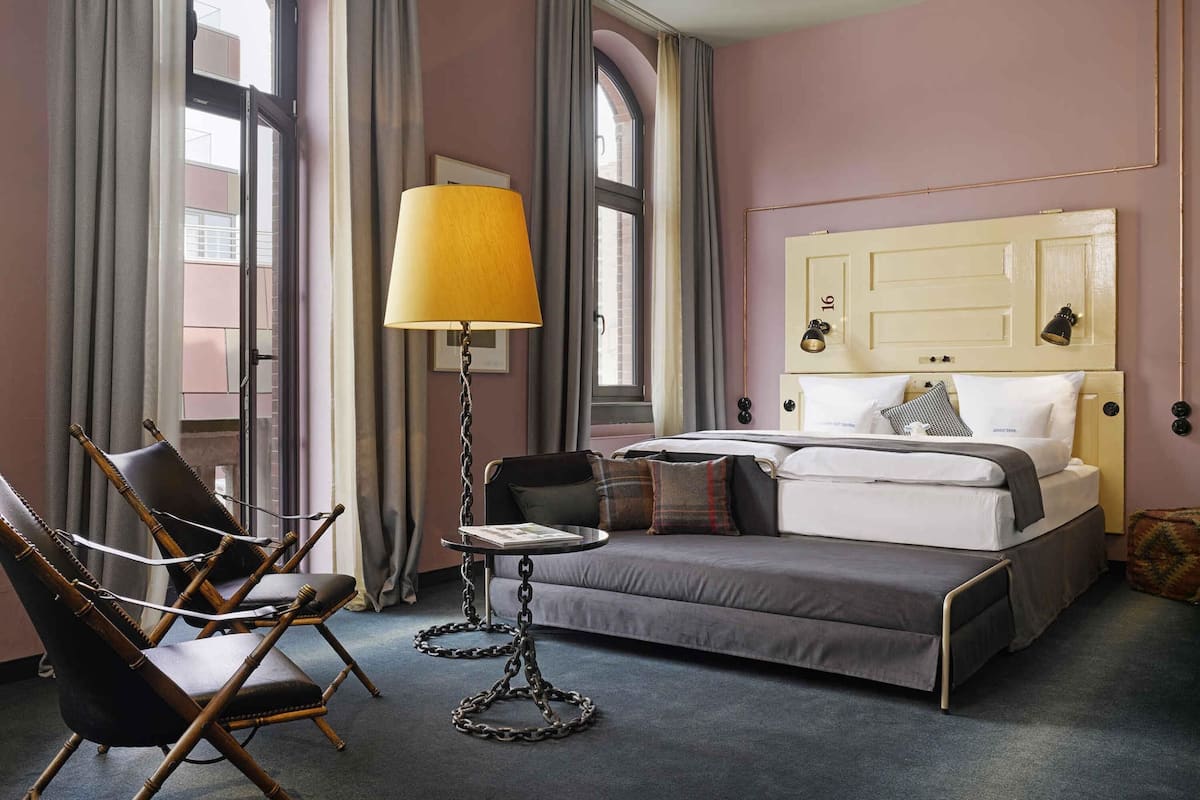Une chambre d’hôtel avec un lit, une chaise, une table et une lampe.