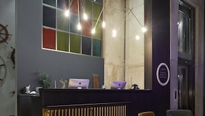 Un comptoir d’accueil avec deux ordinateurs portables, une plante et un panneau indiquant l’accès à un restaurant situé à proximité.