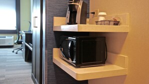 Un coin cuisine équipé d’une machine à café, d’un four à micro-ondes et d’un panier posé sur une étagère.