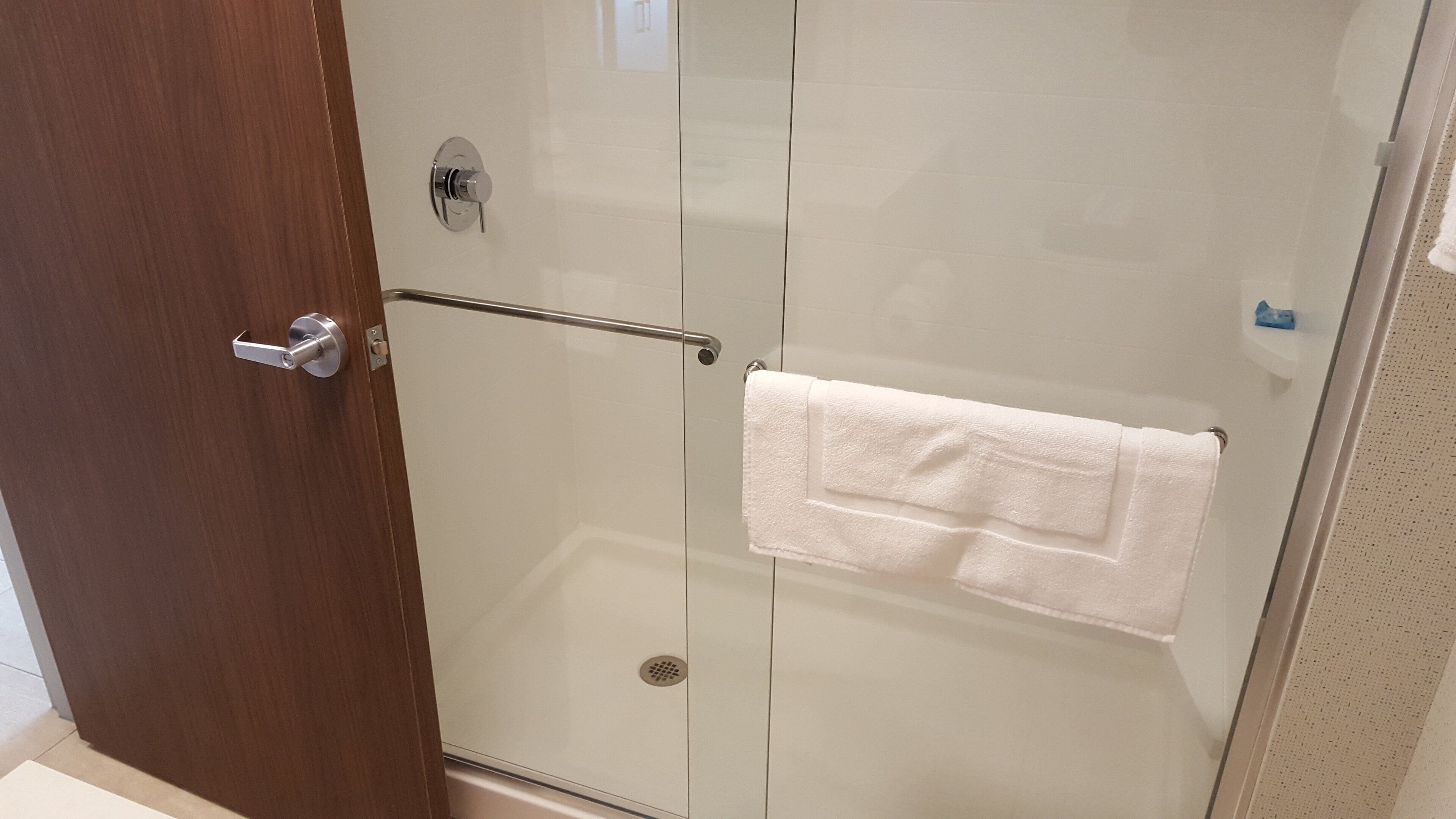 A glass-enclosed shower stall with a towel hanging on the door handle.