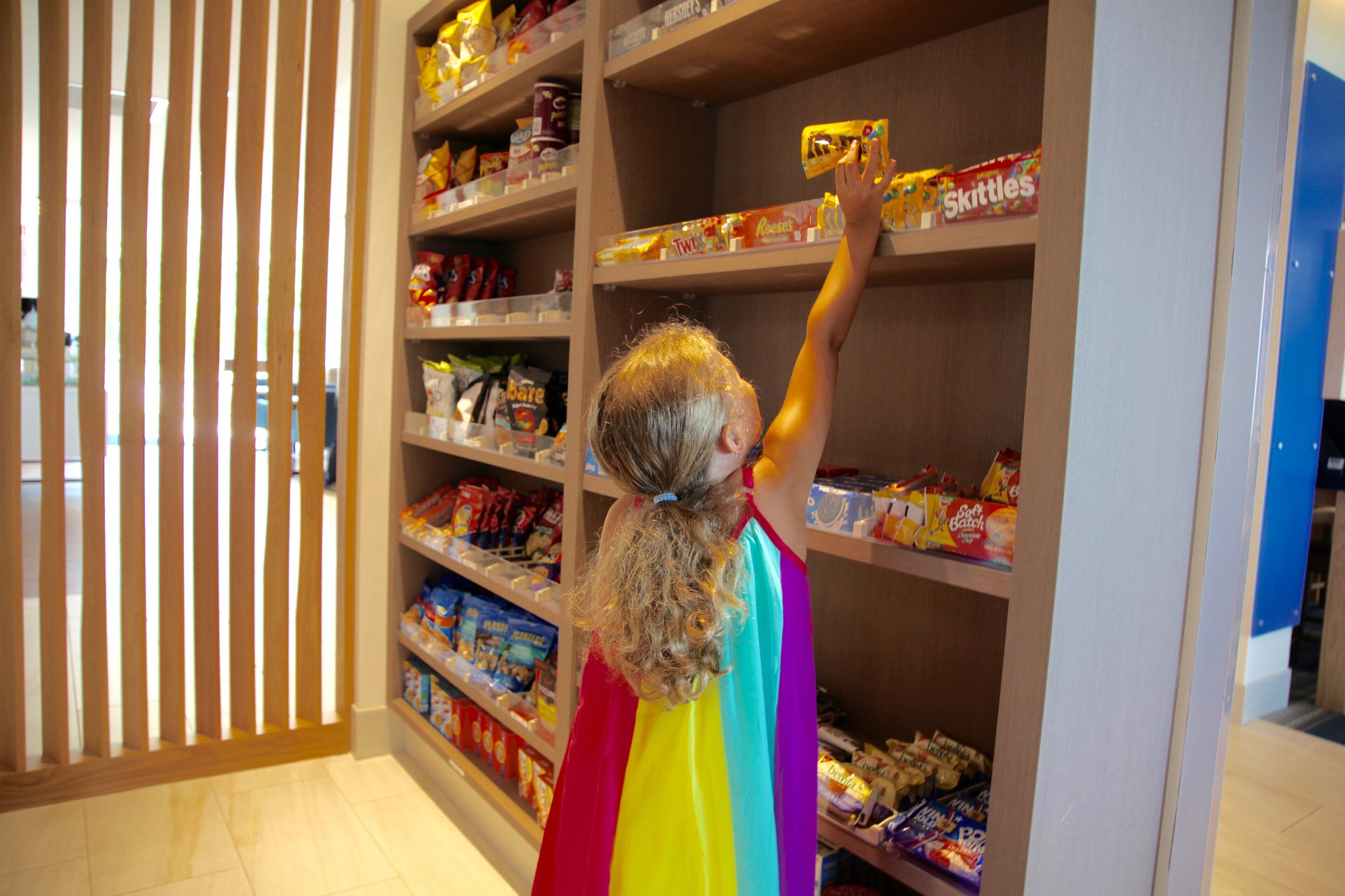 A person reaching for a snack on a shelf in a store.