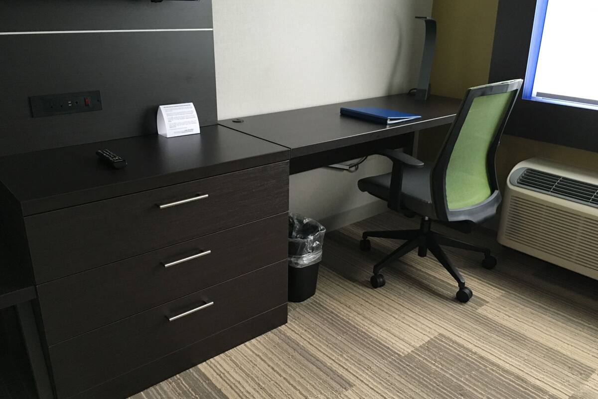 A modern office desk with a computer, a chair, and a trash can.