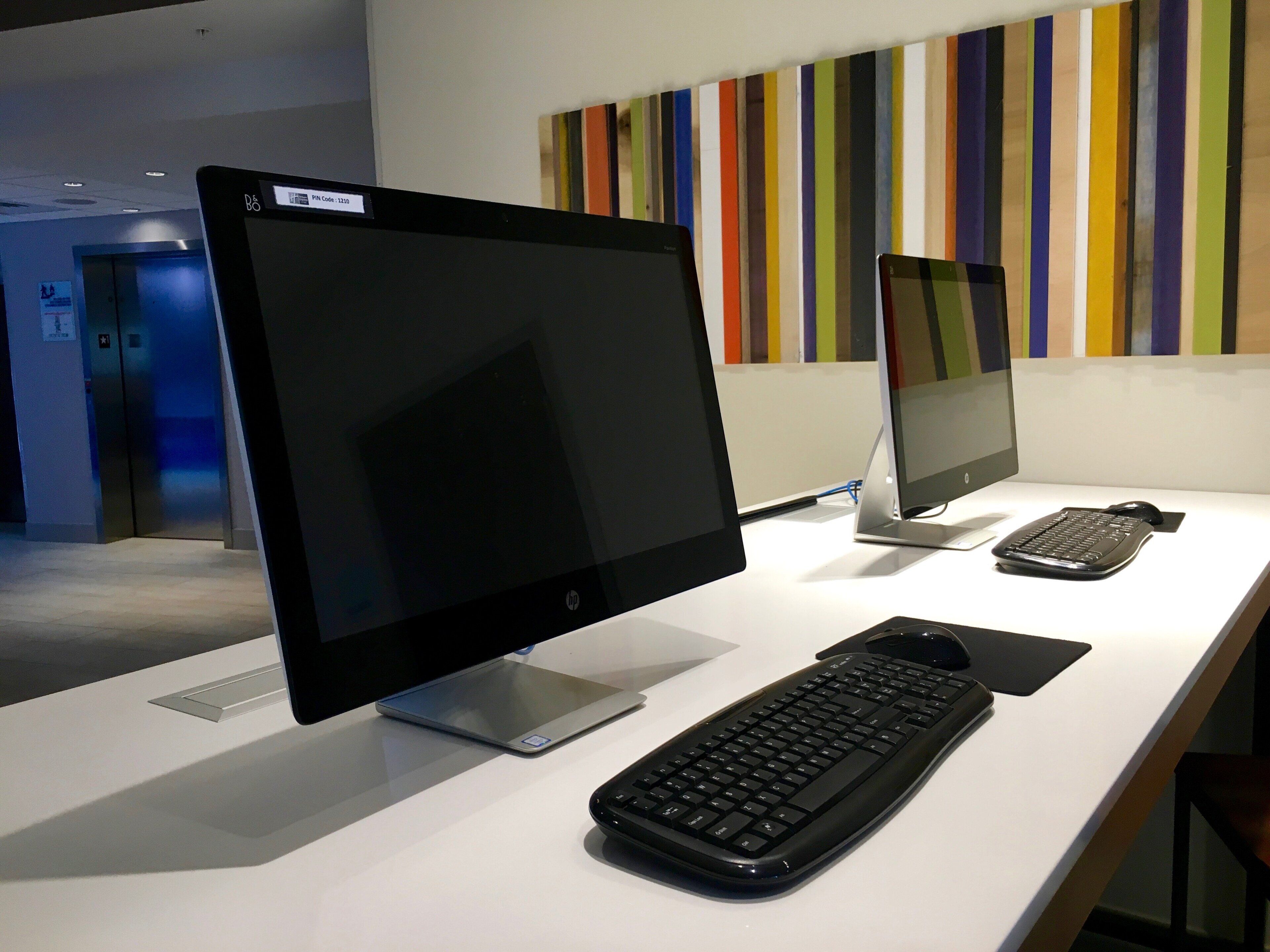 Een bureau met een desktopcomputer, een laptop en een toetsenbord.