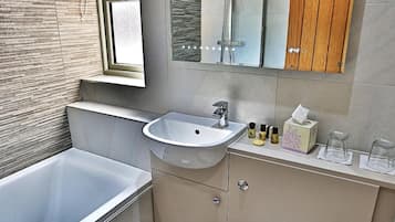 A modern bathroom with a bathtub, sink, toilet, and a large mirror.
