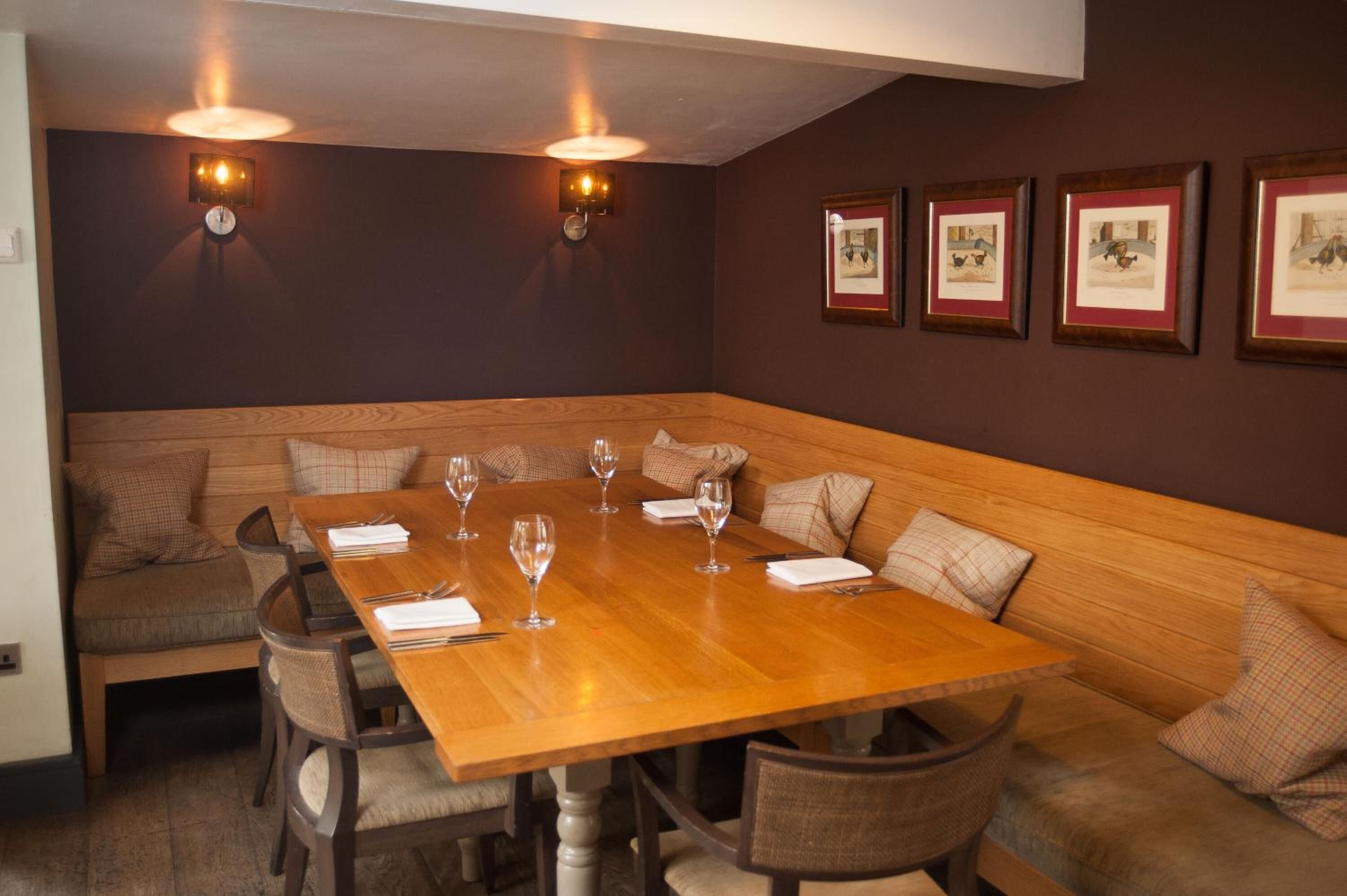 A dining area with a wooden table set for six, surrounded by cushioned benches.