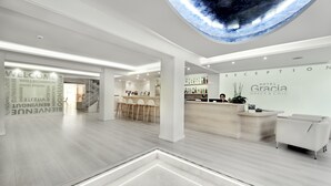 Un hall d’hôtel moderne comprenant un comptoir d’accueil, un espace salon et un grand écran numérique au plafond.