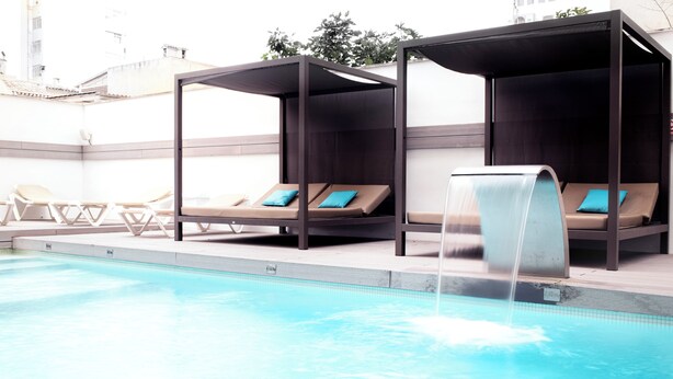 Une piscine équipée de deux chaises longues et agrémentée d’un élément décoratif aquatique.