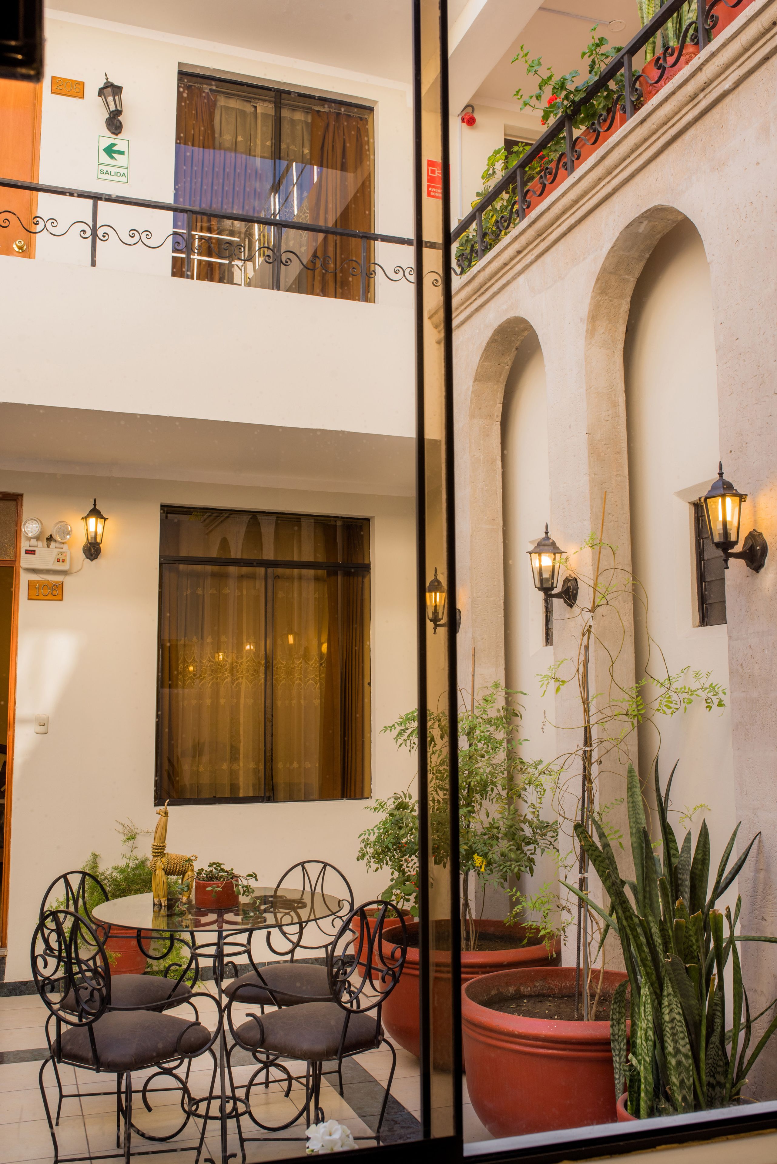 A courtyard with a dining area, potted plants, and a balcony with railings.