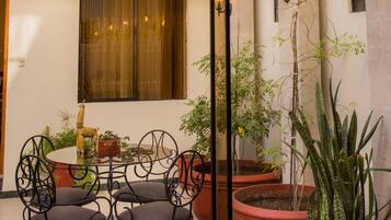 A courtyard with a dining area, potted plants, and a balcony with railings.