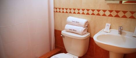A bathroom with a toilet, a sink, and two rolled towels labeled 'Santa Marta'.