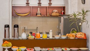 Un bufé con diferentes opciones de comida, entre ellas frutas, verduras y bebidas.