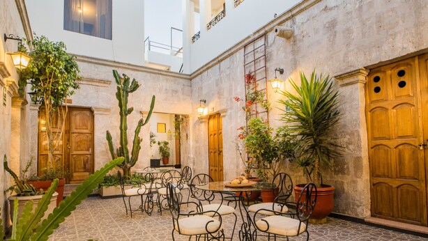 Un patio con suelo de piedra, puertas de madera y plantas en macetas.