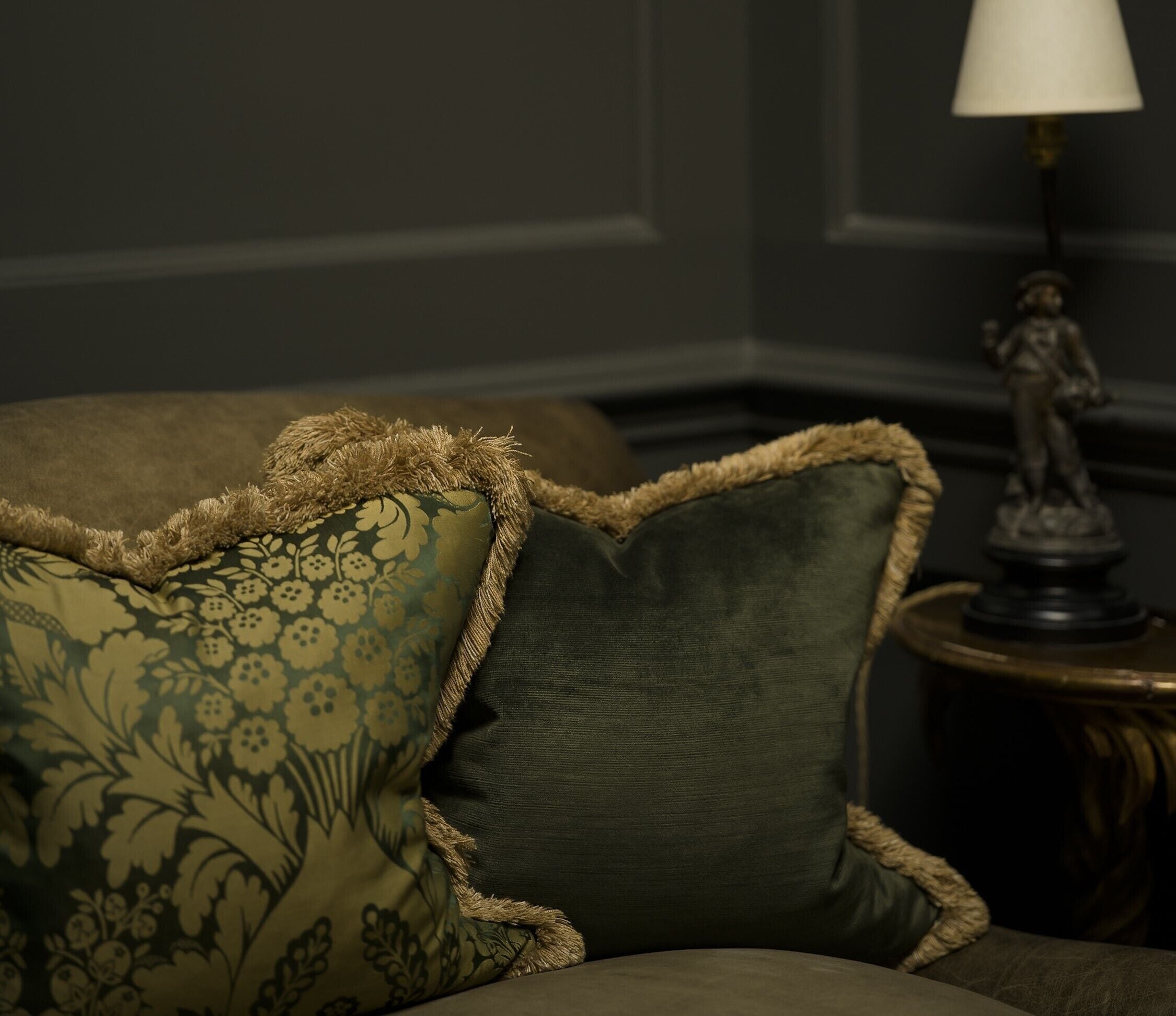 A sofa with floral patterned cushions and a lamp on a side table.