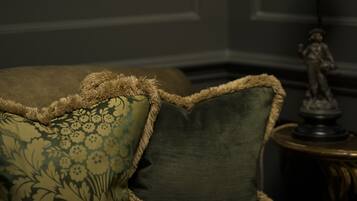 A sofa with floral patterned cushions and a lamp on a side table.