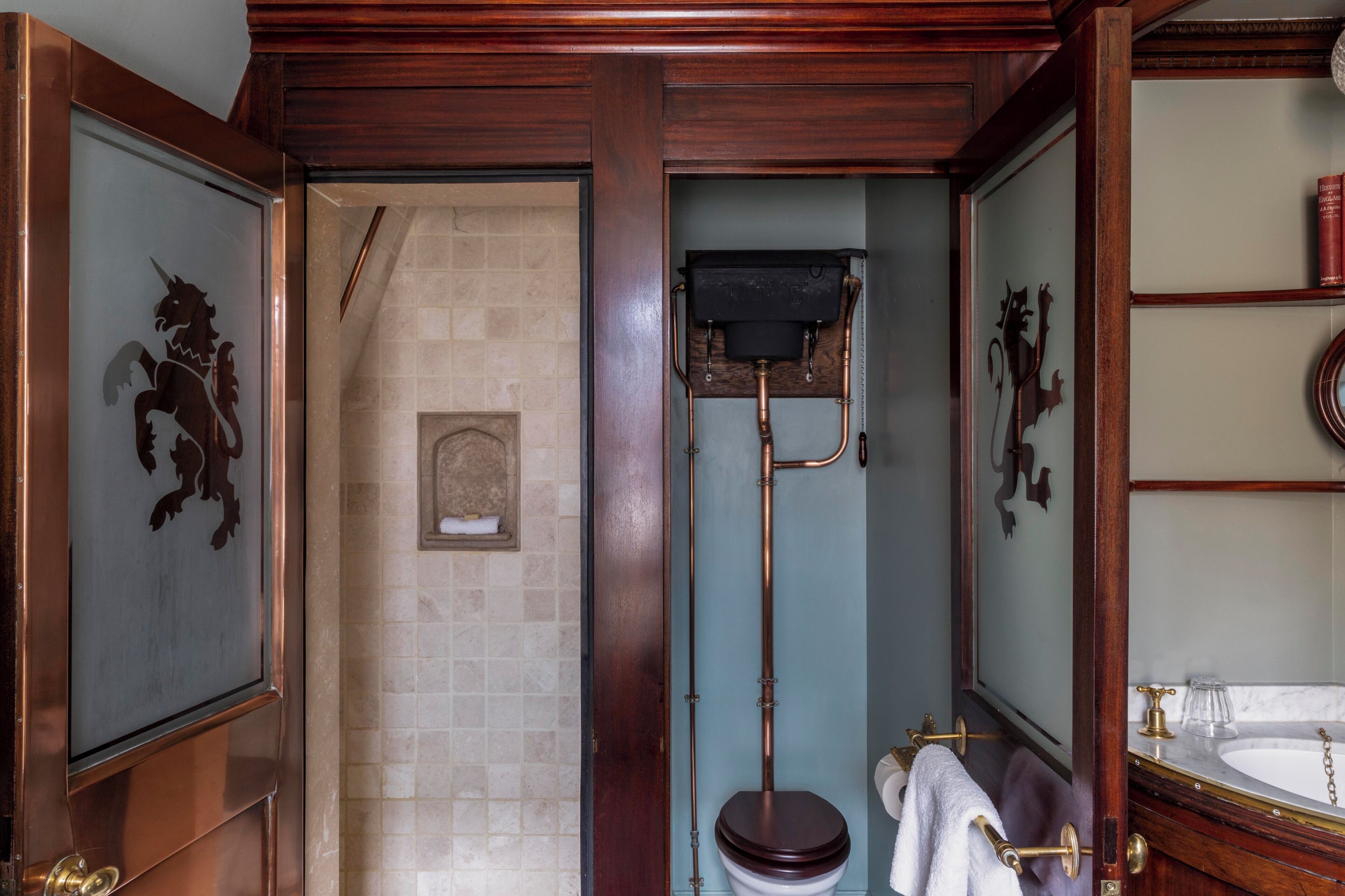 Een badkamer met een houten deur, een toilet, een wastafel en een spiegel.