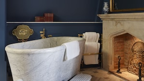 A bathroom with a freestanding bathtub, a marble floor, and a fireplace. - Batty Langley's (London)