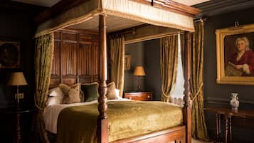 A four-poster canopy bed with a green bedspread, wooden headboard, and matching curtains.
