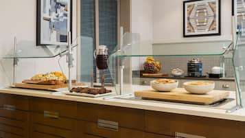 A kitchen counter with various food items, a coffee machine, and a window with blue-tinted glass.