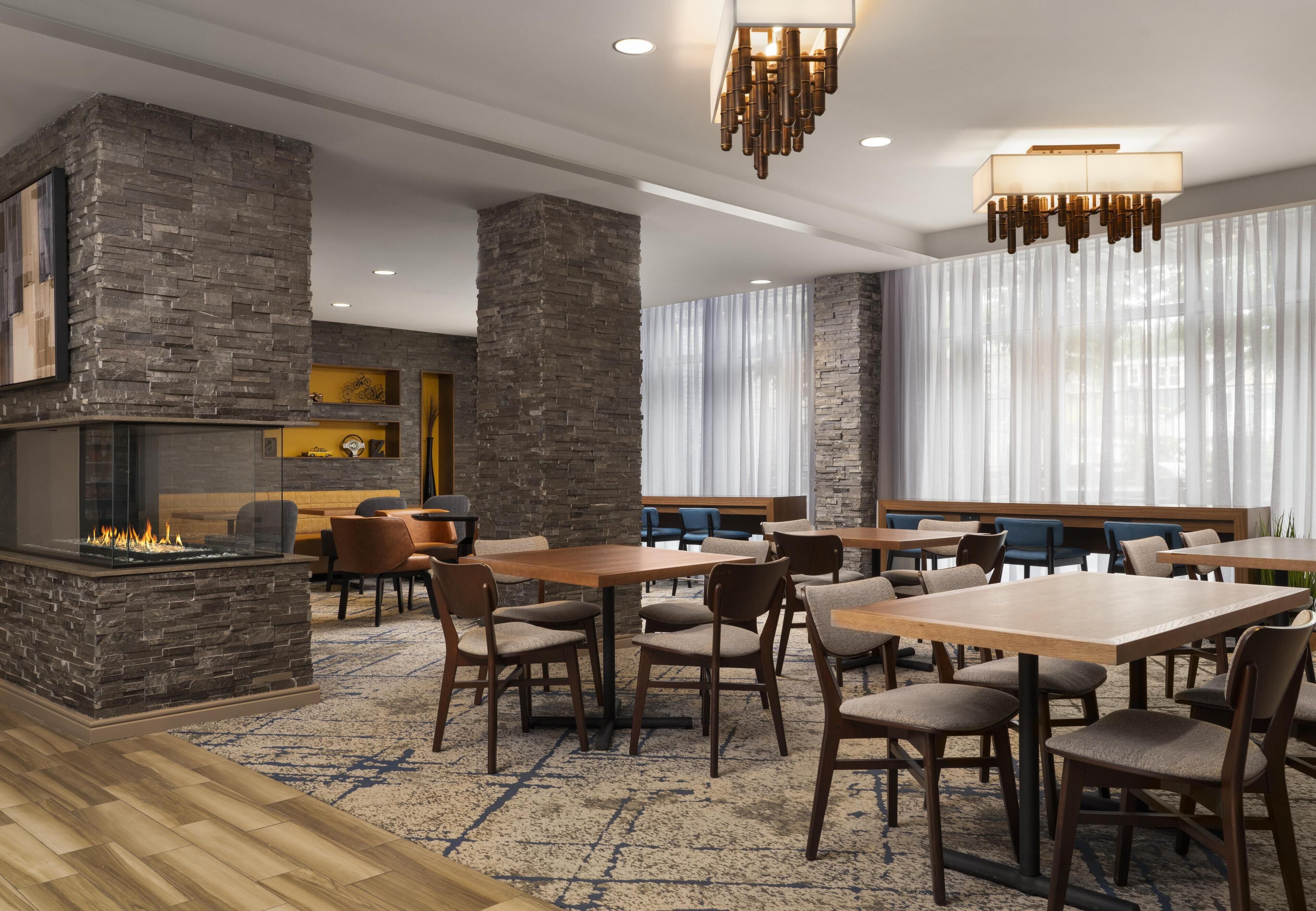 A modern dining area with stone walls, a fireplace, and contemporary furniture.