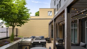 An outdoor patio with a grill, seating, and tables. - Homewood Suites by Hilton Boston Brookline-Longwood Medical (Brookline)