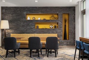 A modern living room with a sofa, three chairs, a lamp, and two shelves with decorative items.