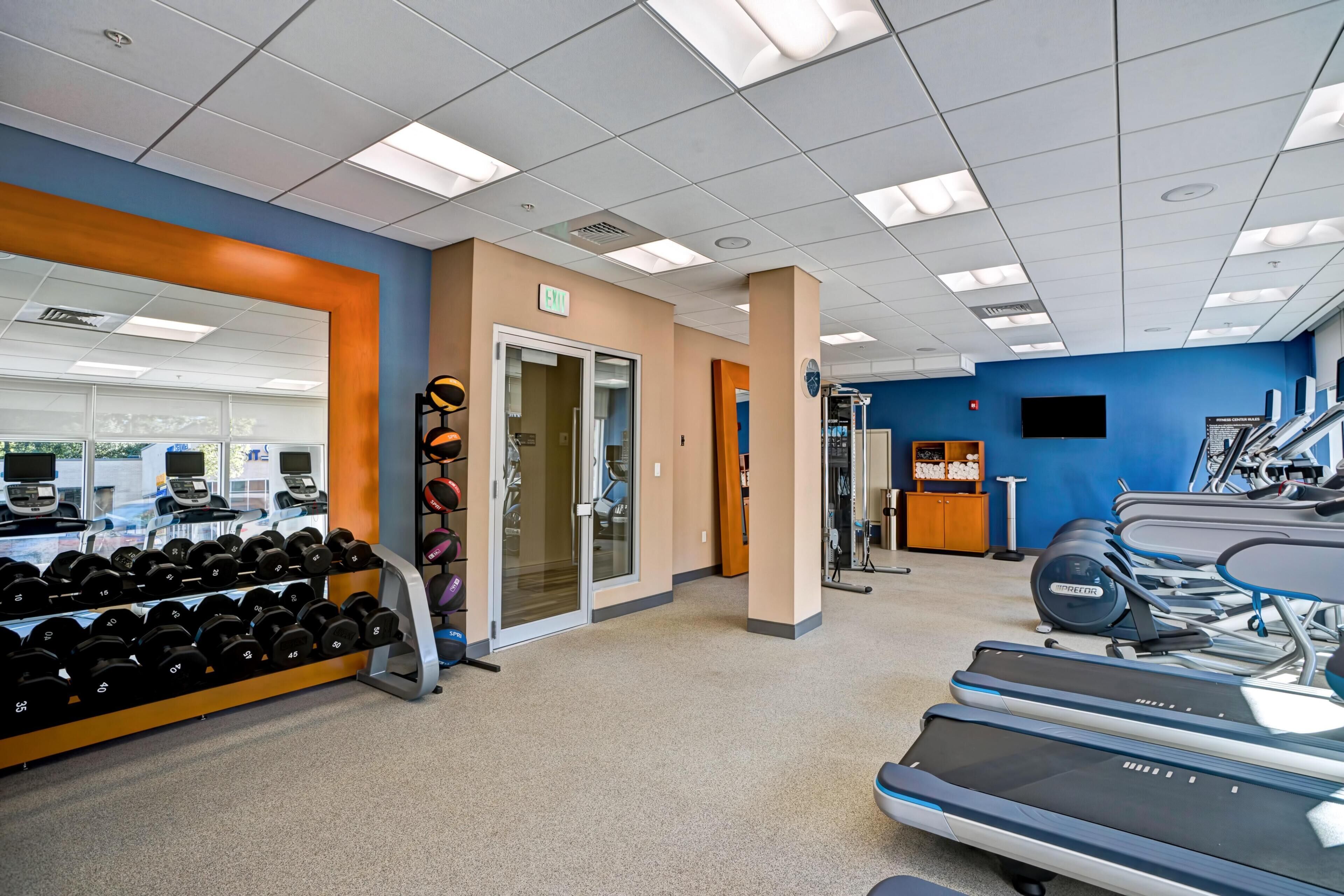Une salle de sport équipée de tapis de course, d’haltères et d’autres appareils d’exercice.