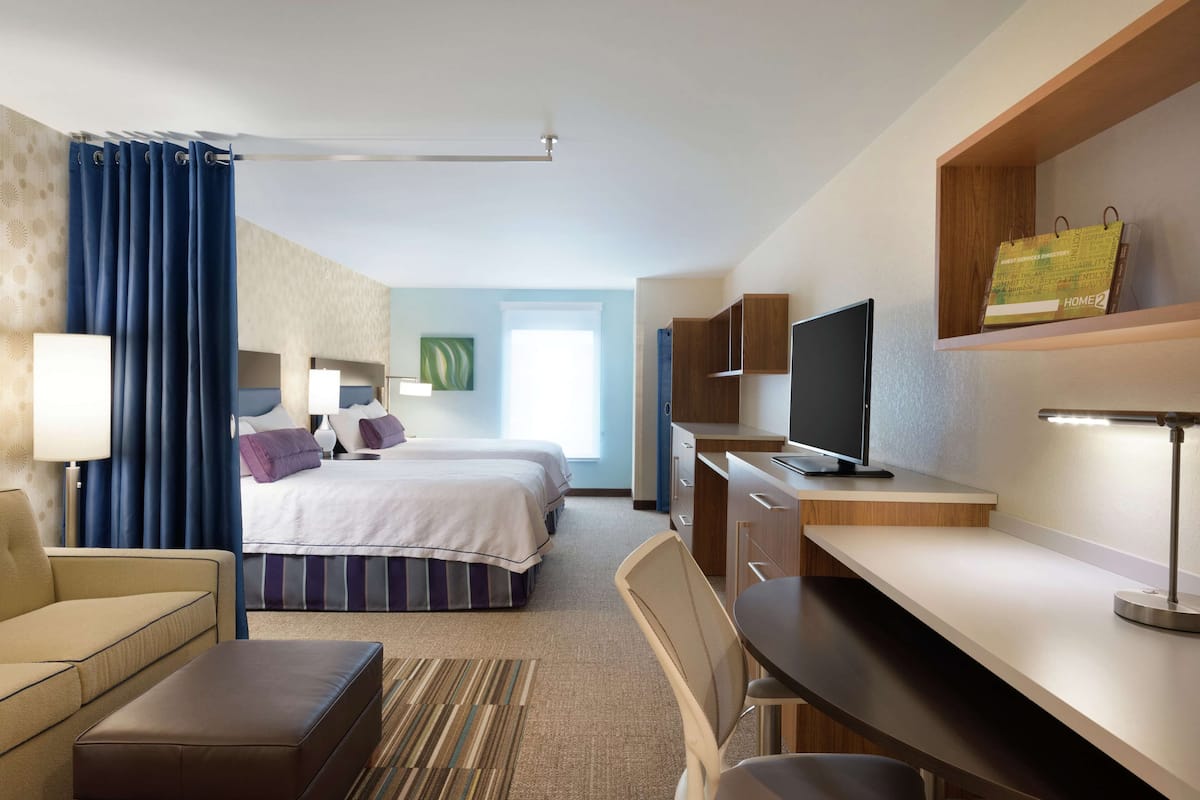 Een hotelkamer met een bed, een bureau, een stoel, een televisie en een lamp.