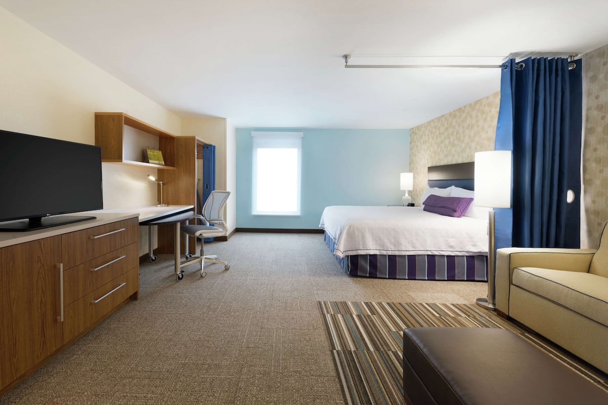 Een hotelkamer met een bed, een bureau, een televisie, een stoel en een bank.