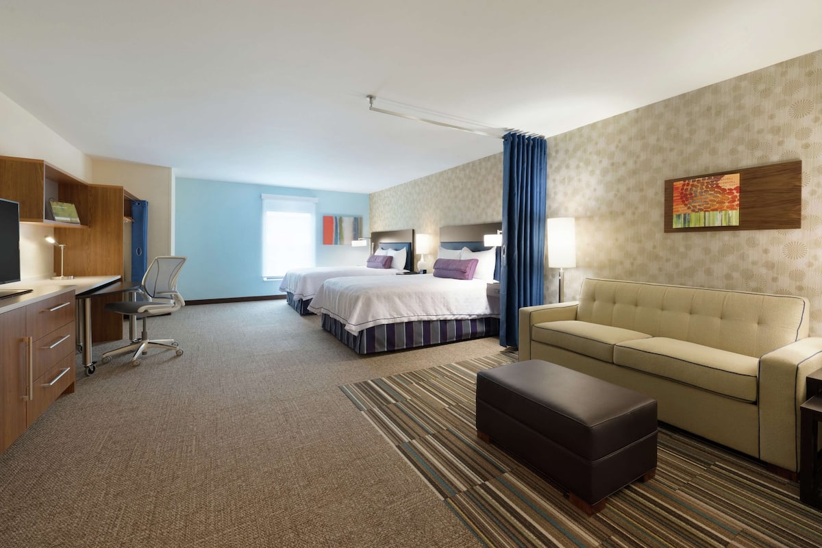 Een hotelkamer met een bed, een slaapbank, een bureau en een stoel.