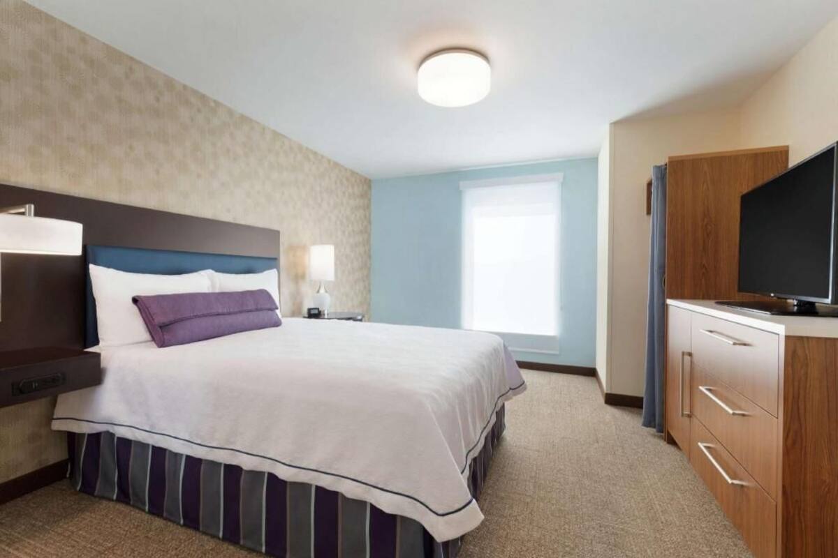 Een hotelkamer met een bed, nachtkastjes, een televisie en een raam.