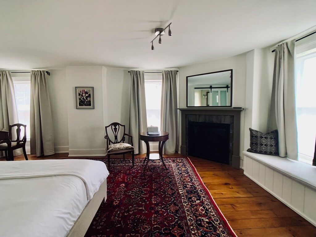 Un dormitorio con una cama grande, una chimenea, un espejo y vistas al exterior.