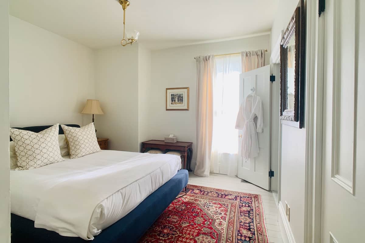 A bedroom with a bed, bedside table, lamp, and a patterned rug.