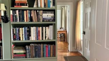 Un couloir avec une bibliothèque remplie de livres, une lampe et une porte au fond.