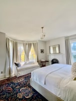 A bedroom with a large bed, a smaller bed, a fireplace, and a patterned carpet.