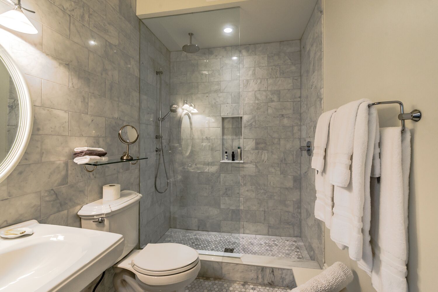 A modern bathroom with a shower, toilet, and sink.