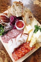 A charcuterie board with various meats, cheeses, and bread.