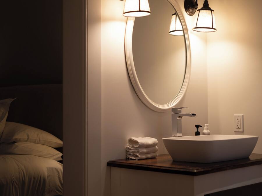 A bathroom with a large mirror, a white sink, and a towel stack.