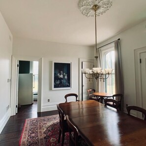 A dining area with a wooden table, chairs, a chandelier, and a rug.