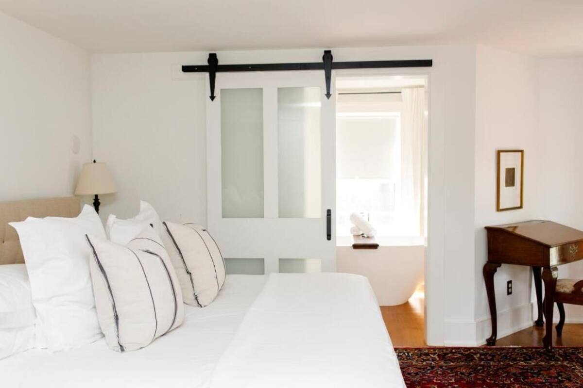 A hotel room with a large bed, a desk, a chair, and a window with curtains.