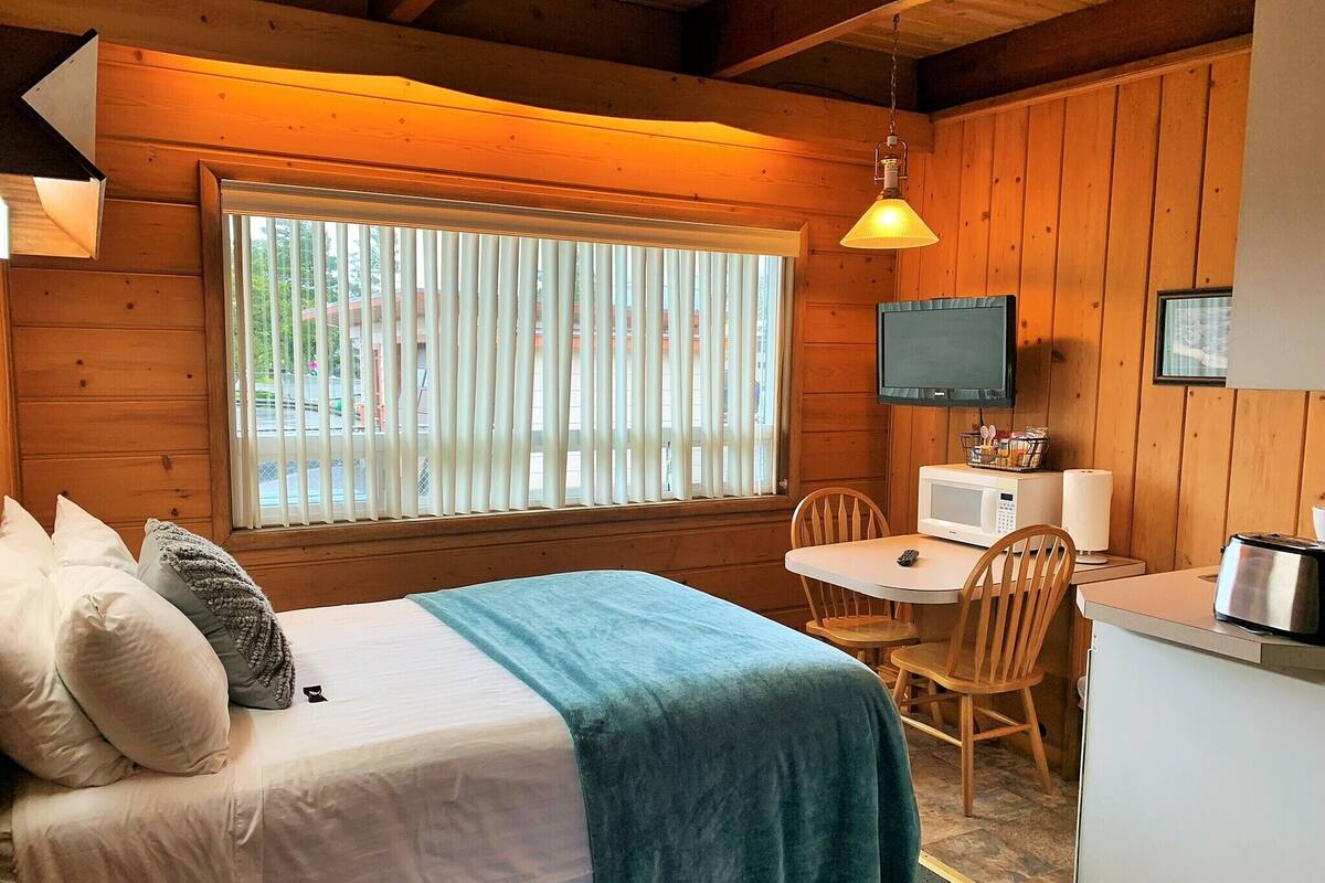 A cozy cabin-style room with a bed, a dining table, and a TV.