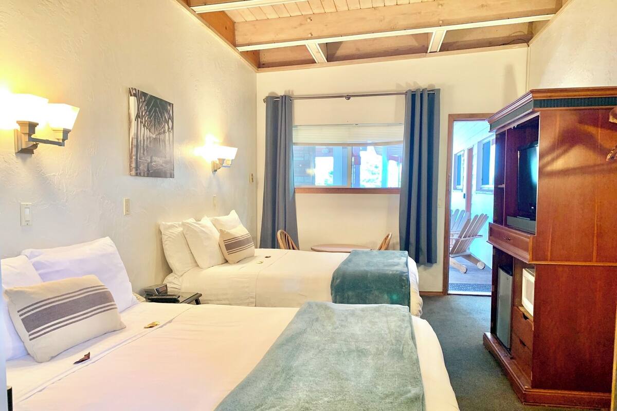 A hotel room with two beds, a television, and a wooden cabinet.