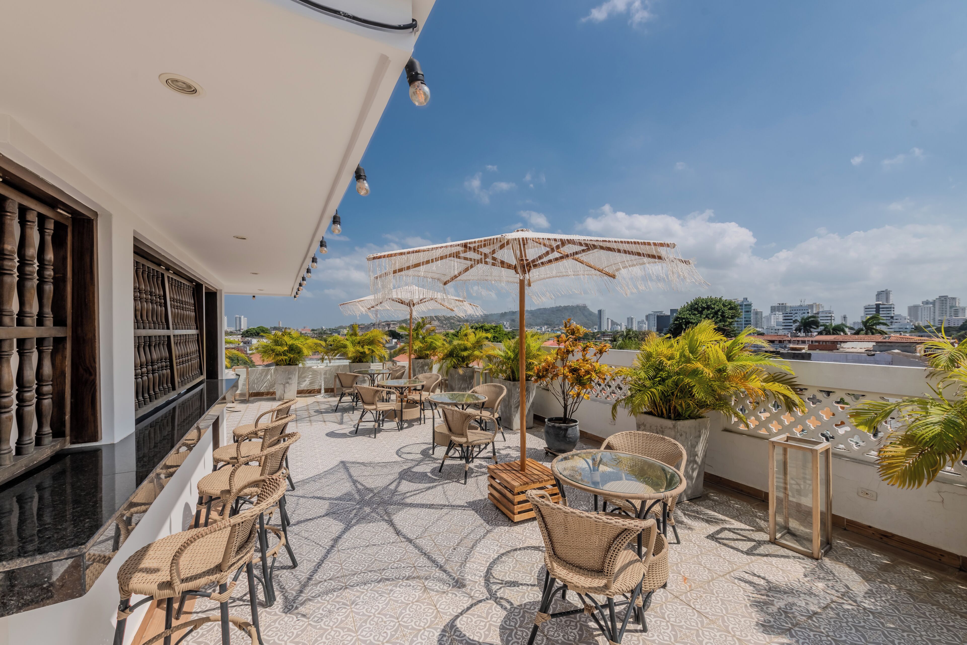 Eine Dachterrasse mit Sitzgelegenheiten im Freien, Kübelpflanzen und Blick auf die Stadt.