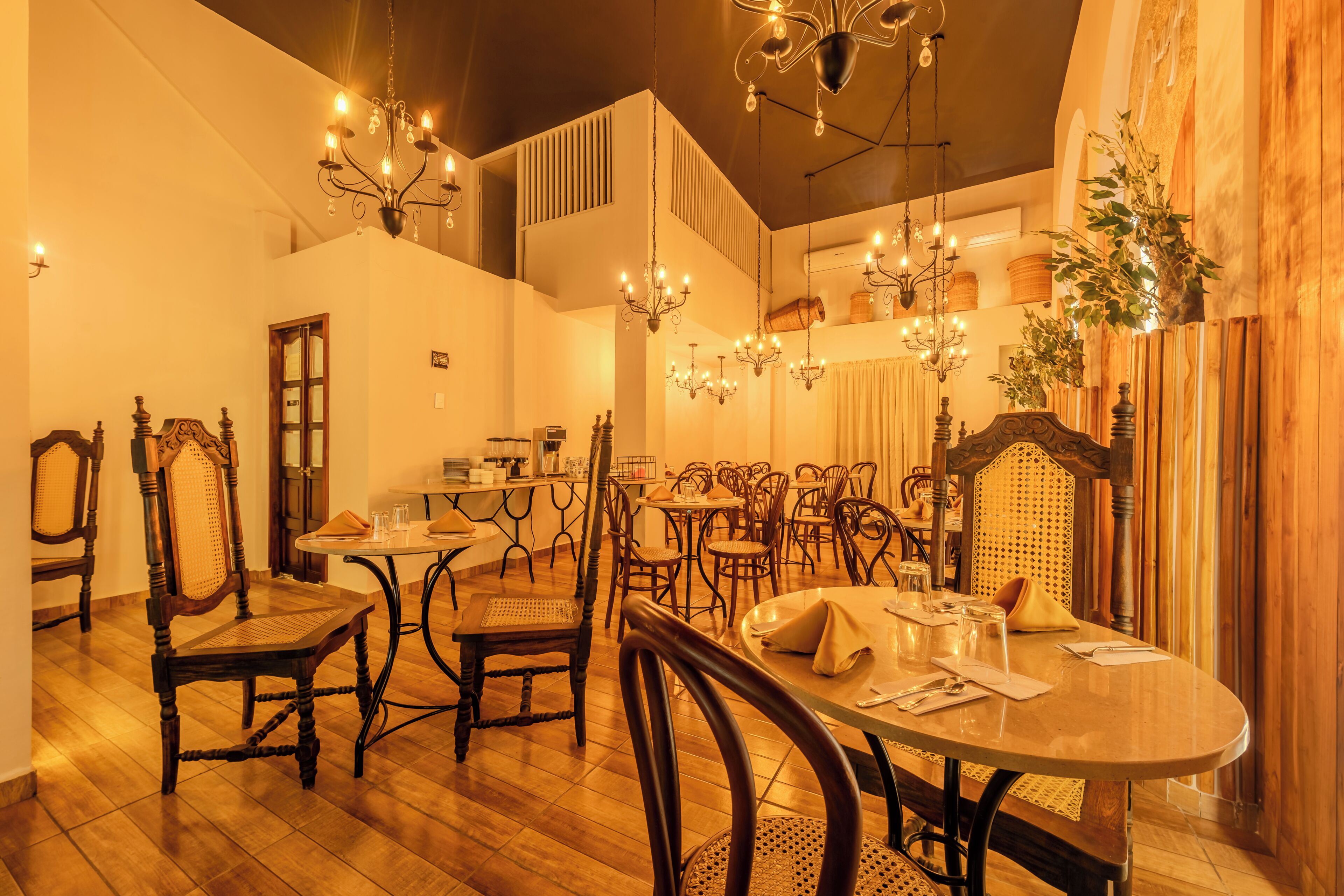 A dining area with wooden furniture, chandeliers, and a high ceiling.